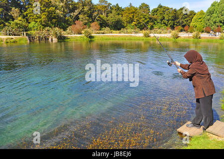 Verschleierte Frau Angeln am See Garten Stockfoto