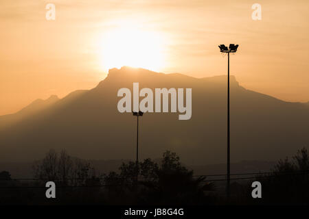 Telegrafenmasten Kabel in den Sonnenuntergang mit Bergen im Hintergrund Stockfoto