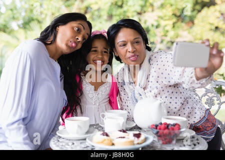 Generationsübergreifende Familie nehmen Selfie zusammen vom Frühstückstisch zu Hause sitzend Stockfoto