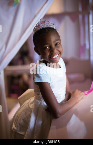 Porträt von fröhliches Mädchen mit Krone zu Hause stehen Stockfoto
