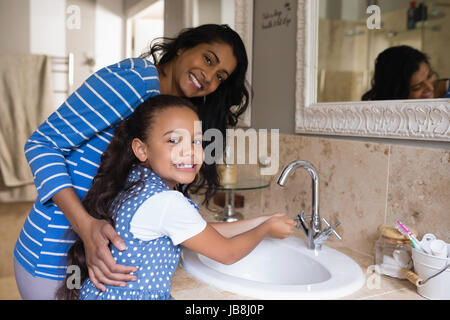 Porträt von lächelndes Mädchen mit Mutter waschen Hände am Waschbecken im Bad Stockfoto