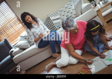 Großmutter und Enkelin Färbung buchen im Wohnzimmer zu Hause Stockfoto