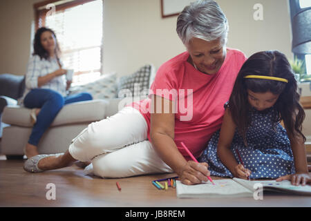 Großmutter und Enkelin Färbung buchen im Wohnzimmer zu Hause Stockfoto
