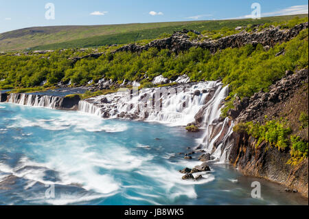 Hraunfossar ist eine sehr schöne isländische Wasserfall im Westen der Insel. Es stammt aus dem Lavafeld und ergießt sich in den Fluss Hvita mit einem unglaublich blauen Wasser. Langzeitbelichtung. Stockfoto