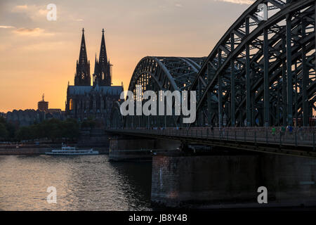 Rhein bei Sonnenuntergang mit Blick auf den Kölner Dom (Kölner Dom) mit den Hohenzollern Brücke Hohenzollernbrücke) im Vordergrund, Köln Stockfoto