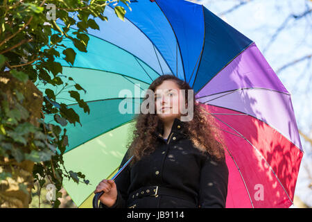 Eine Junge Hübsche Frau Steht Mit Einem Bunton Schirm in der Wintersonne Stockfoto