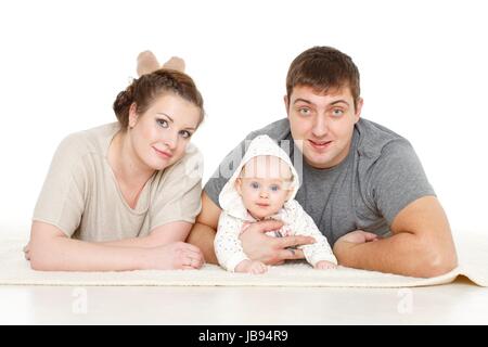 Junge Eltern mit ihrer süßen Tochter liegen auf einem weißen Hintergrund. Glückliche Familie. Stockfoto