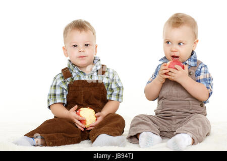 Zwei kleine Jungs mit frischen Äpfeln sitzen auf einem weißen Hintergrund. Gesunde Ernährung. Stockfoto