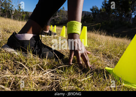 Frau, berühren die Ziellinie beim laufen durch Training Zapfen an einem sonnigen Tag Stockfoto