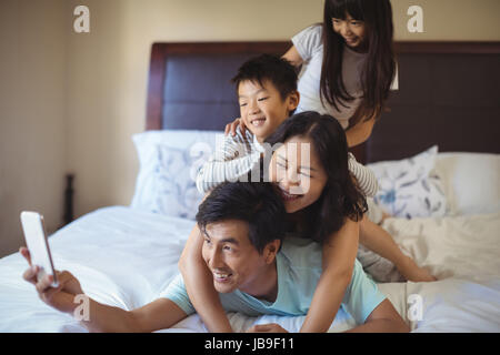 Glückliche Familie, die eine Selfie auf Handy im Schlafzimmer zu Hause Stockfoto