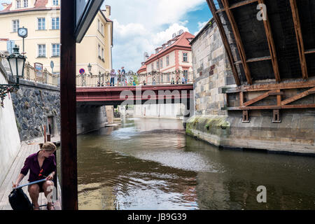 Prag, Tschechische Republik. 28. Mai 2017. Junge Frau malt in den Kanal des Flusses Moldau unter dem letzten Bogen der Karlsbrücke, Prag. Stockfoto