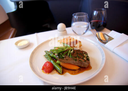 SINGAPORE AIRLINES, Singapur - 22. Juli 2016: Gegrilltes Lammfilet in Rosmarinjus mit Karotten, Spargel, Cherry-Tomaten und Kartoffelgratin in Busine Stockfoto