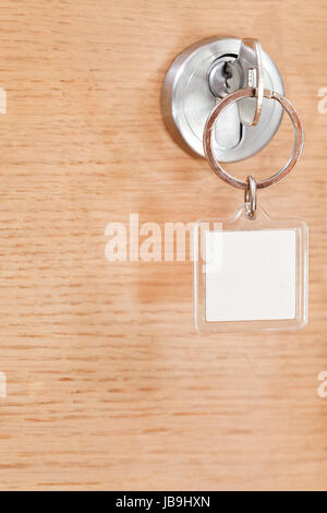 Stahl-Taste mit leere Quadrat Schlüsselanhänger im Schloss der Holztür Stockfoto