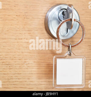 Stahl-Taste mit leere Quadrat Schlüsselanhänger im Schloss der Holztür hautnah Stockfoto