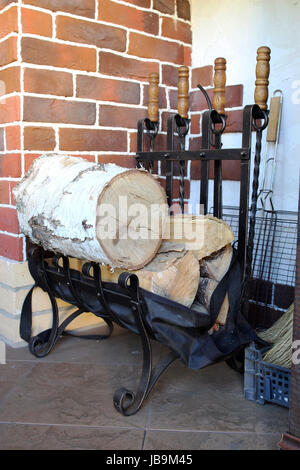 Kamin-Zubehör und Werkzeuge in der Nähe von einer Mauer mit Kamin Stockfoto