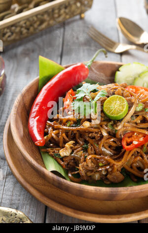 mir Goreng Mamak oder mi Goreng, indonesischen und malaysischen Küche, würzig gebratene Nudeln mit Esstisch aus Holz. Frisch heiß mit gedünstetem Rauch. Stockfoto