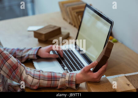 Mittleren Bereich der weibliche Führungskraft mit Laptop am Schreibtisch im Büro mit gedrückter einer Holzplatte Stockfoto