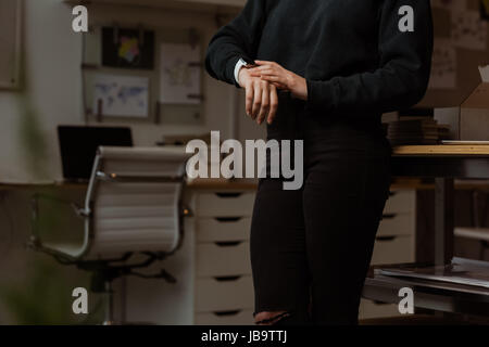 Mittleren Bereich der weibliche Führungskraft mit Smartwatch in office Stockfoto