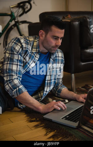 Mann mit Laptop im Wohnzimmer zu Hause Stockfoto
