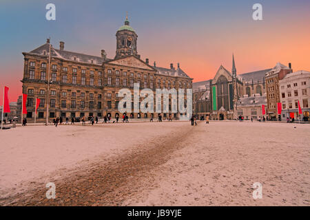 Verschneite Dam in Amsterdam Niederlande im Winter bei Sonnenuntergang Stockfoto
