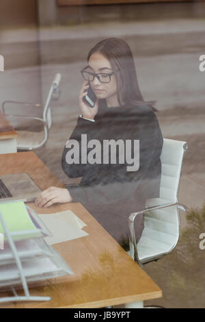 Weibliche Führungskraft telefonieren mit Handy am Schreibtisch im Büro Stockfoto