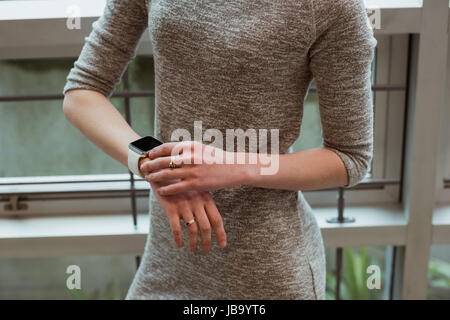 Mittleren Bereich der weibliche Führungskraft mit Smartwatch in office Stockfoto