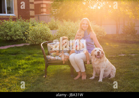 Familie, Haustier, Haustiere und Menschen Konzept - glückliche Familie mit Labrador Retriever Hund Sommergarten Stockfoto