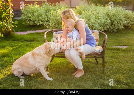 Glückliche Familie mit ihrem Hund spielen, an einem sonnigen Tag. Stockfoto