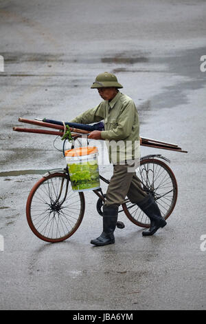 Alter Mann und Zyklus im Regen, Ninh Binh, Vietnam Stockfoto