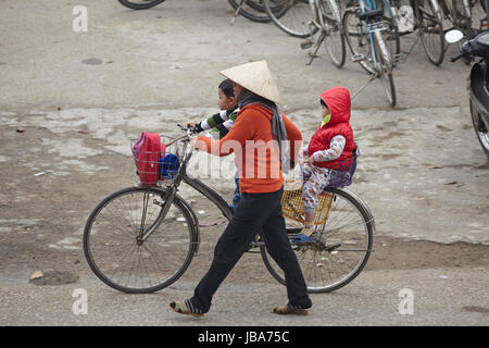 Frau drängen Kinder auf Zyklus, Ninh Binh, Vietnam Stockfoto