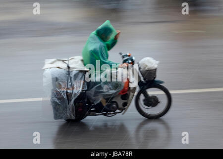 Mann auf Roller im Regen, Ninh Binh, Vietnam Stockfoto