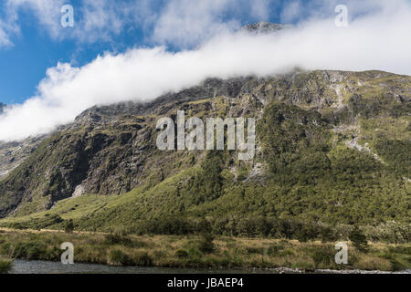 Fiordland-Nationalpark, New Zealand - 16. März 2017: Landschaft der Affe Bach fließt im Tal unter hohen Berggipfel teilweise bedeckt mit weißen c Stockfoto