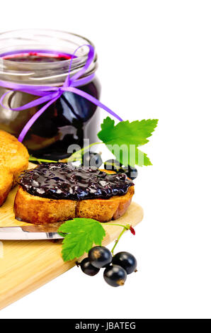 Scheiben geröstetes Brot, ein Glas mit schwarzen Johannisbeeren Marmelade auf dem Brett isoliert auf weißem Hintergrund Stockfoto