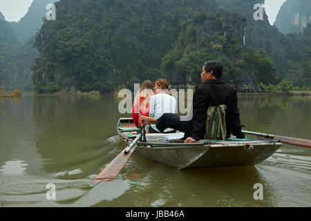 Touristen auf Tam Coc (drei Höhlen) Boot Reise auf Ngo Dong Fluss, (UNESCO World Herritage Area), in der Nähe von Ninh Binh, Vietnam Stockfoto