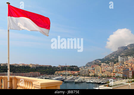 Nationalflagge, modernen Wohnbauten und Luxus-Yachten im Hafen Hercule unter blauem Himmel in Monte Carlo, Monaco. Stockfoto
