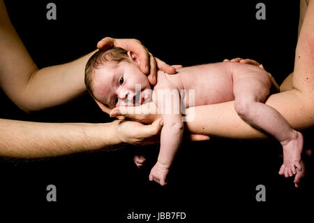 Ein Kleines Neugeborenes Baby Wird Auf der Hand der Mutter Naturheilsteine Und von Anspieltipp Haenden Beschuetzt Und Schaut-auflösende aus, Freigestellt Vor Schwarzem Hintergrund. Stockfoto