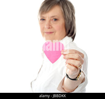 Konzentrieren Sie sich auf rosa Papierherz. Im Alter von Frau hält es in der Nähe von Kamera Stockfoto