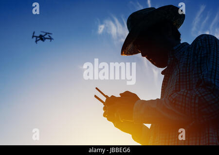 Silhouette der Landwirt mit Drohne Fernbedienung smart farming Landwirtschaft und die Zukunft der Landwirtschaft Stockfoto