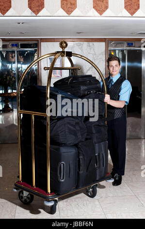 Bell Boy Schieben Karren beladen mit Gepäck auf der Gäste-Zimmer Stockfoto