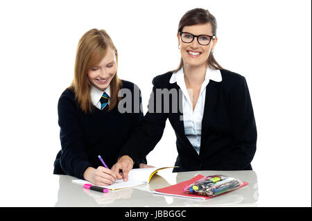 Bebrillten Lehrer die Fehler in ihrem Notizbuch Studenten aufzeigen und mit Blick auf die Kamera. Stockfoto