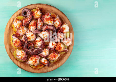 Eine obenliegende Foto von Pulpo a la Gallega, eine Krake mit gekochten Kartoffeln, typisch spanisches Gericht, auf einer traditionellen hölzernen Platte eine Krickente Hintergrund Witz Stockfoto