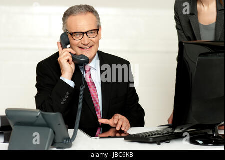 Im Alter von Geschäftsmann Kommunikation am Telefon mit Sekretär stehend neben Stockfoto