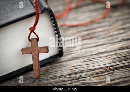 Nahaufnahme des hölzernen Christian Kreuz Halskette neben Bibel Stockfoto