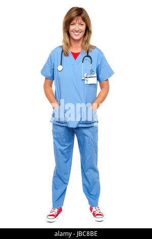 In voller Länge Portrait von blonde Arzt in einheitlichen posiert mit Hände in der Tasche. Stockfoto