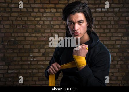 Junge malaysische Boxer tragen Hoodie und Gurte um die Hände wickeln Stockfoto