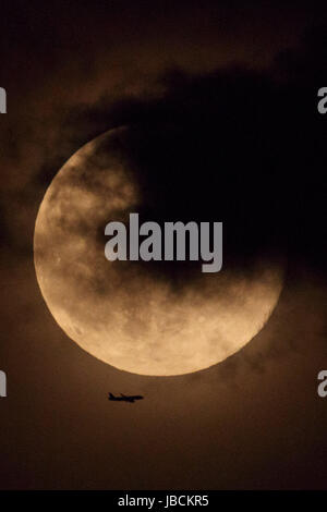 Ein Flugzeug fliegt vorbei an der Erdbeere Mond am 10. Juni 2017, Tokio, Japan. Es ist ein astronomisches Phänomen, das in dieser Zeit des Jahres, tritt auf, wenn der Mond am nächsten an den Horizont und leuchtet in einem rötlichen Ton. Erdbeere Mond ist benannt nach der Erdbeeren pflücken-Saison im Juni beginnt. Bildnachweis: Rodrigo Reyes Marin/AFLO/Alamy Live-Nachrichten Stockfoto