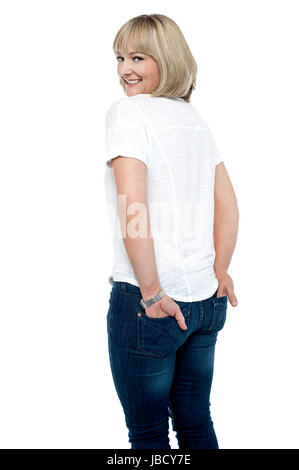 Elegant gekleidete Frau mit Händen auf der Rückseite Tasche Jeans. Rücken-Tuning und Blick in die Kamera. Stockfoto
