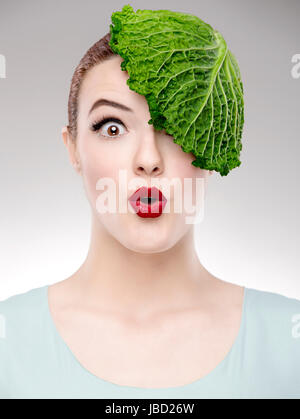 Porträt einer Frau, die zur Veranschaulichung einer Vegan-Konzepts mit einem Kohl auf dem Kopf Stockfoto