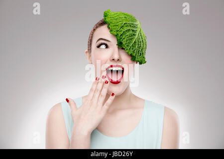 Porträt einer Frau, die zur Veranschaulichung einer Vegan-Konzepts mit einem Kohl auf dem Kopf Stockfoto