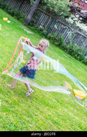 Kleines Mädchen macht riesigen Seifenblase in außen Stockfoto